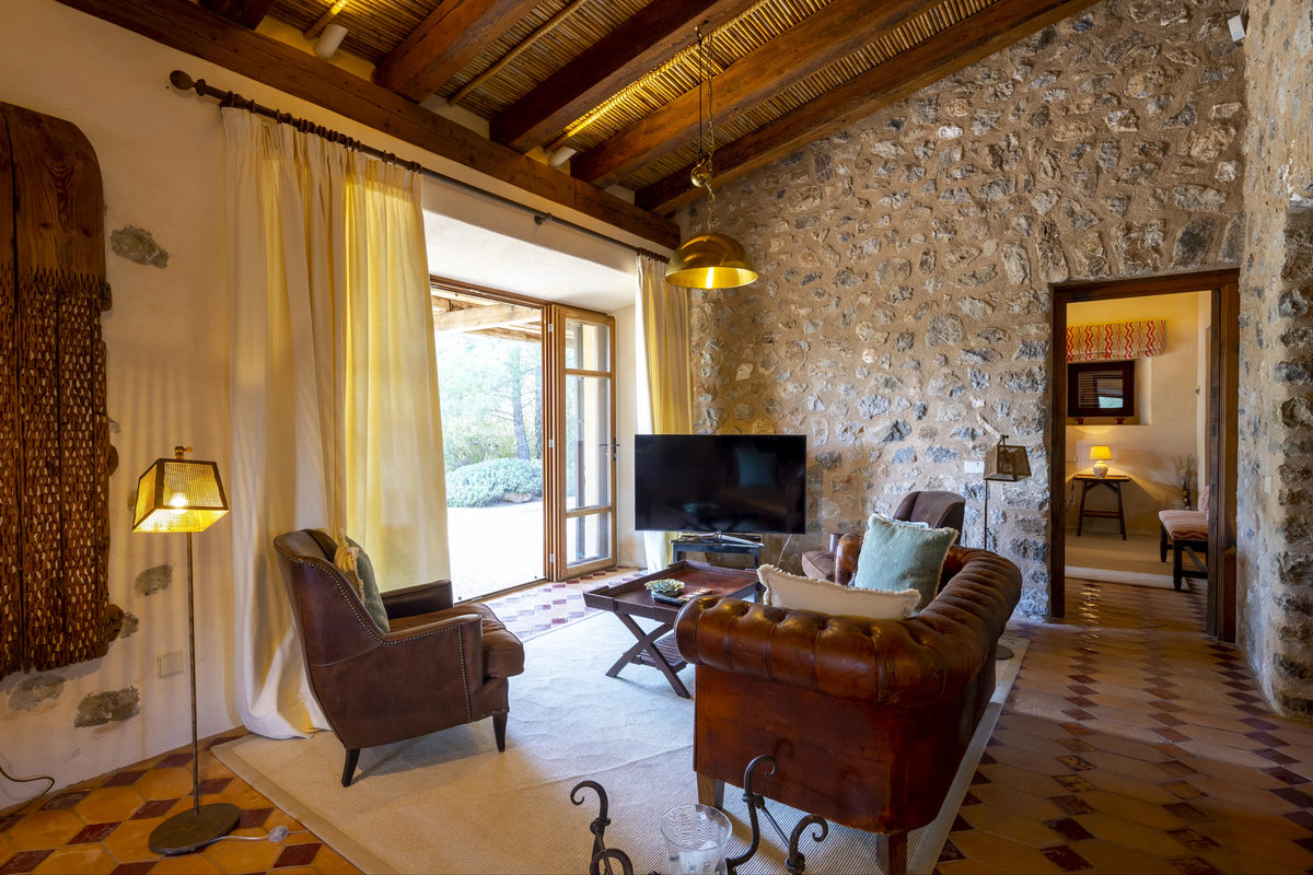 Living room of The Lodge with leather sofas, stone walls and the door open onto the garden