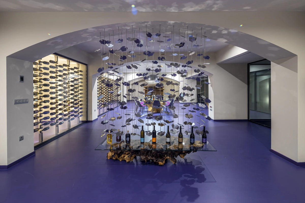 Tasting table with Es Fangar wines under a hanging installation of metal leaves