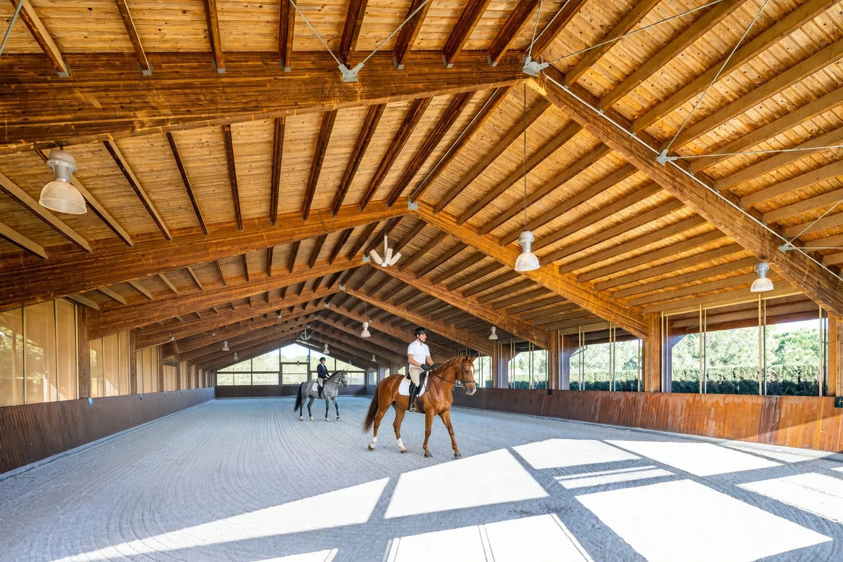 Jinetes a caballo en el picadero cubierto de Es Fangar bajo su techo de madera